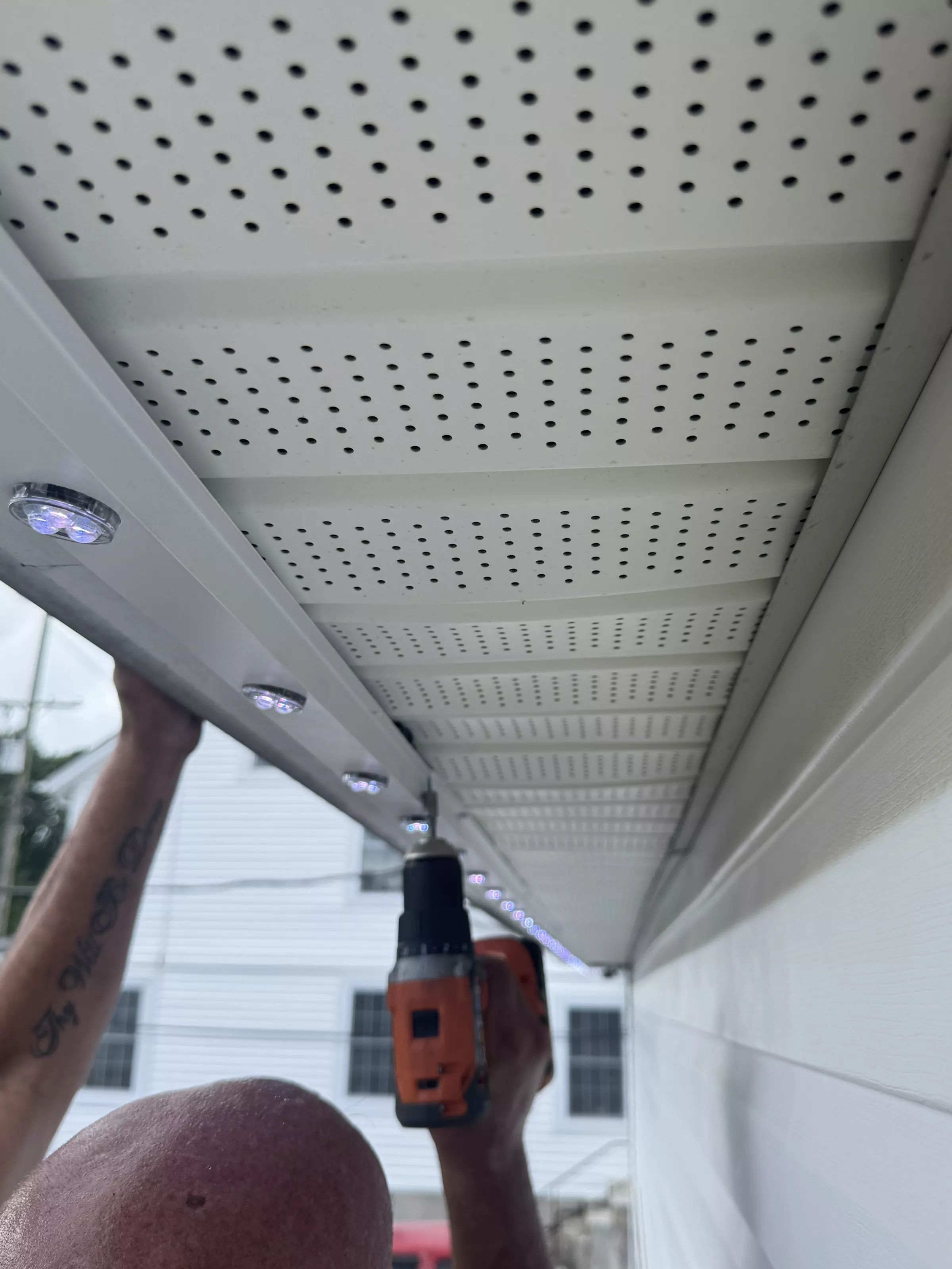 Installer drilling a light into the soffit