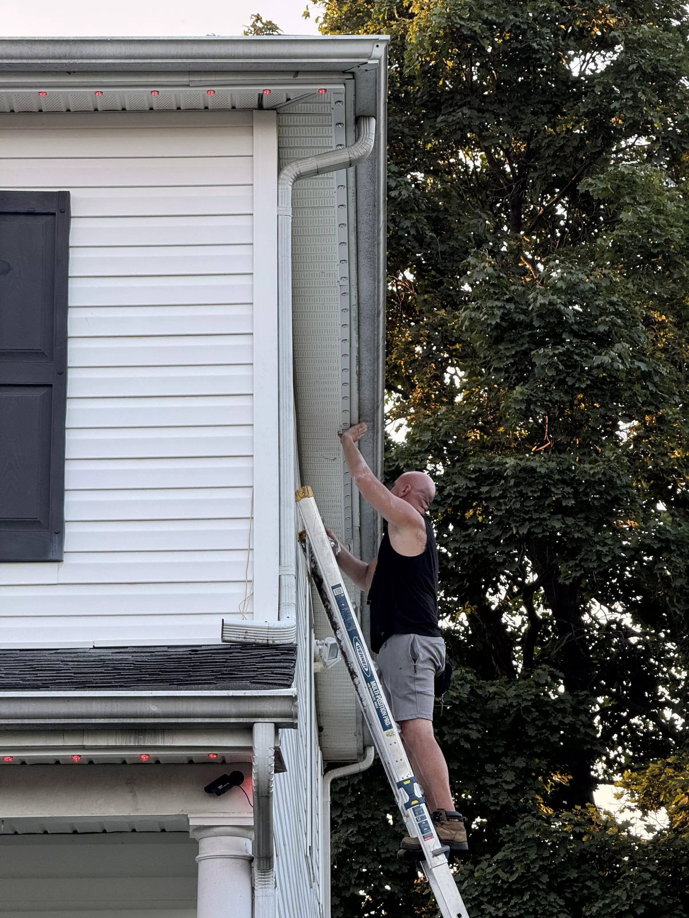 Installer on a ladder beside the roofline