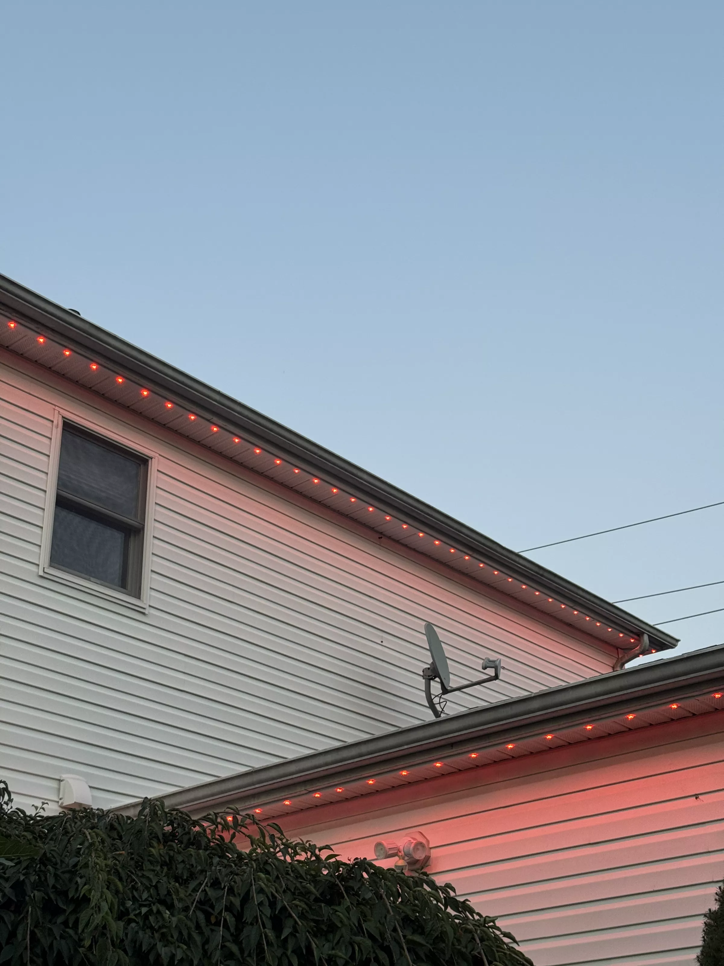 Home with colored roofline lights at dusk