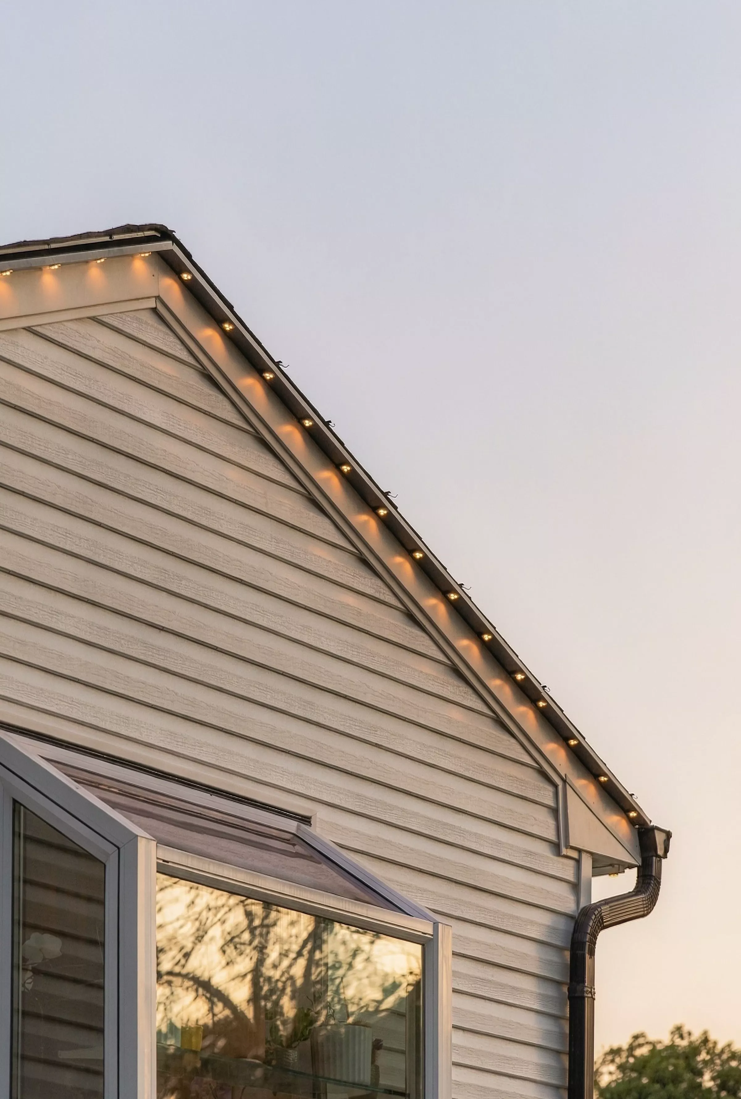 Gable end with warm roofline lights at dusk