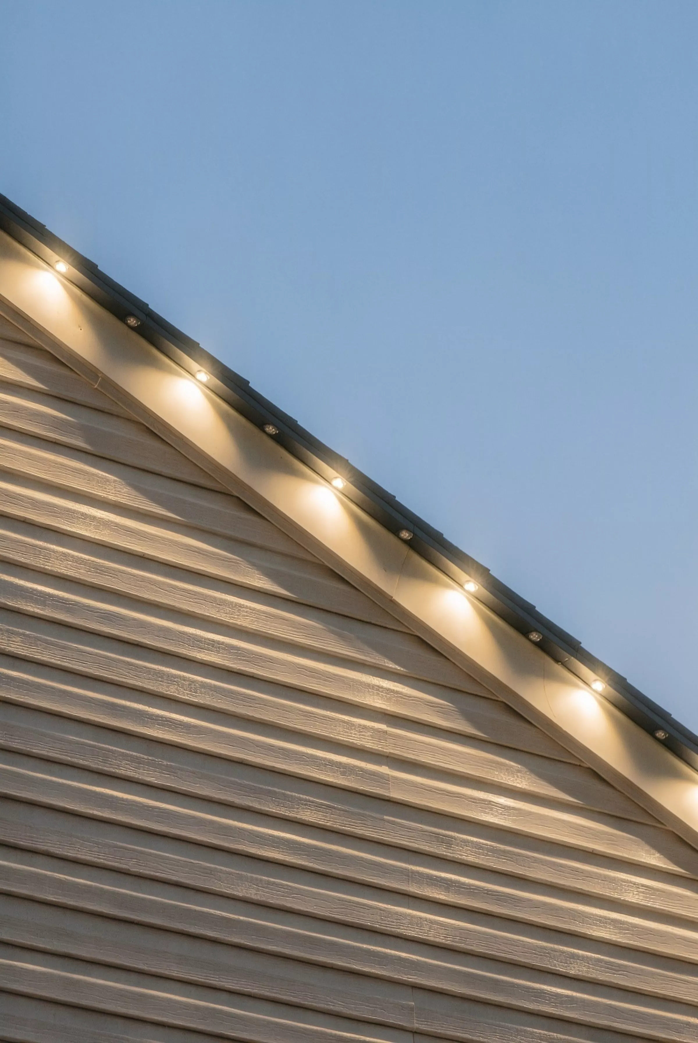 Warm white lights following a roofline at dusk